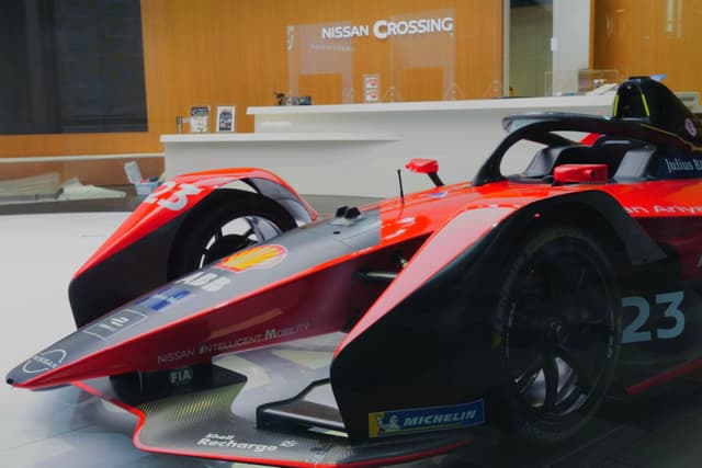 A red and black Formula E race car displayed indoors with the number 23 on its side