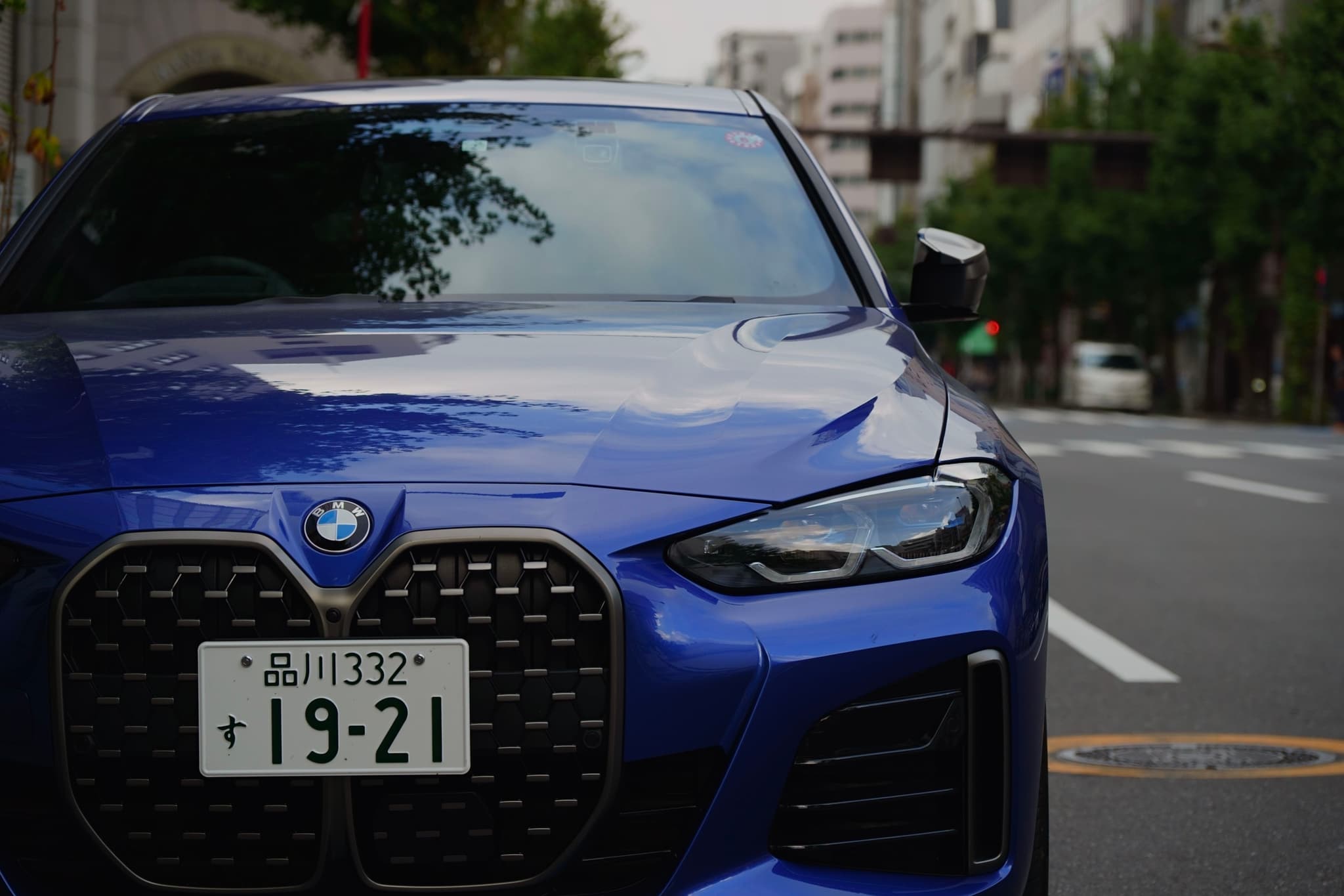 A blue BMW car with a Japanese license plate parked on a city street