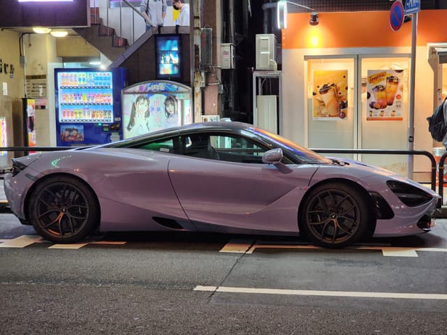 A sleek, purple McLaren 750s parked in Ginza, Tokyo on a busy shopping night, with buildings and a vending machine for company