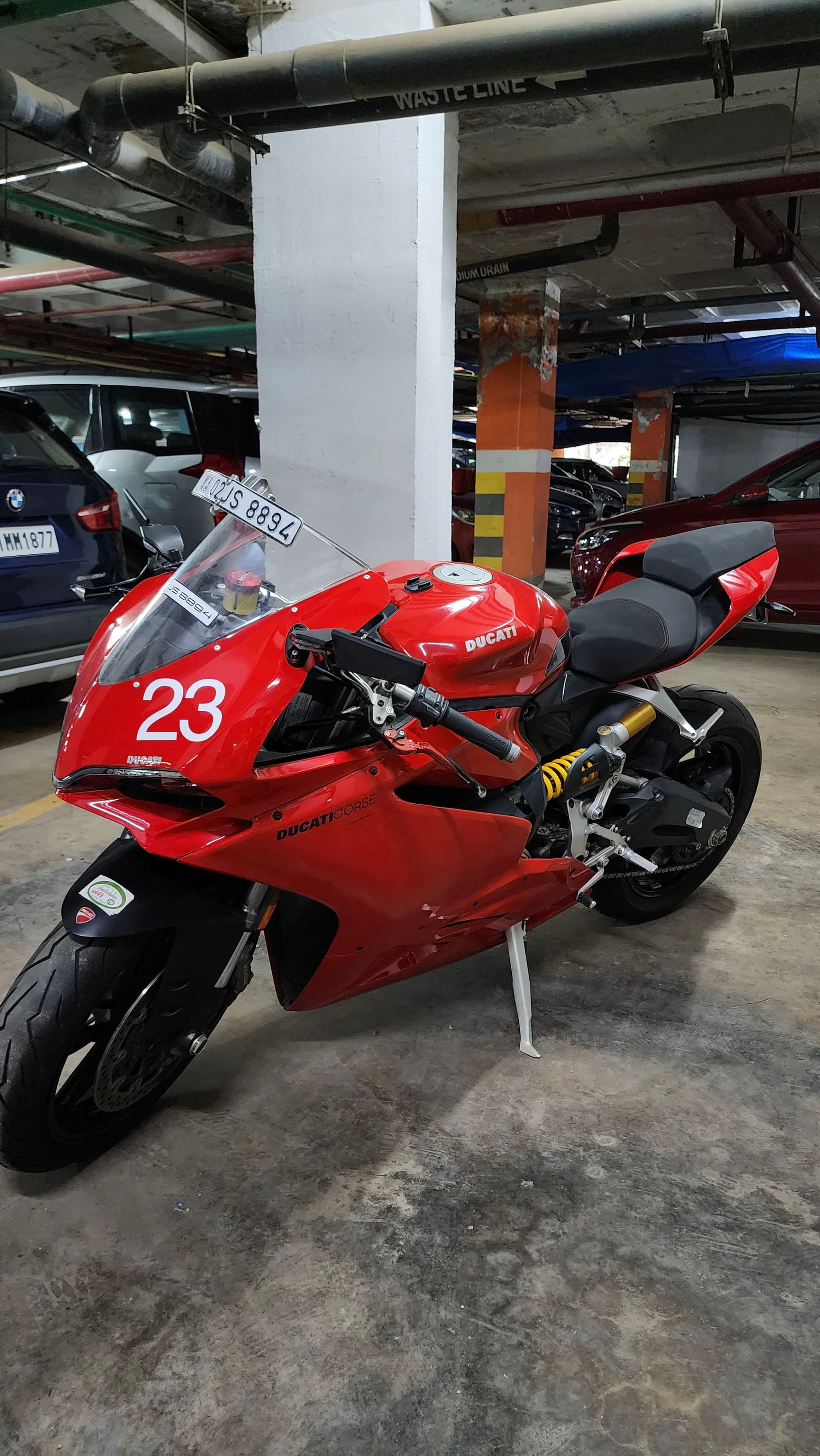 A red sports motorcycle with the number 23 on its front fairing is parked in an indoor parking garage